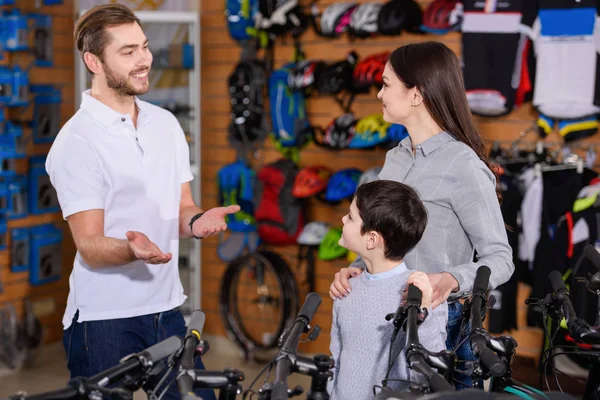 微笑年轻工作者显示自行车在自行车商店的母亲和儿子 — 图库照片