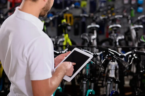 若い男が自転車屋で空白の画面を持つデジタル タブレットを使用してのショットをトリミング — ストック写真