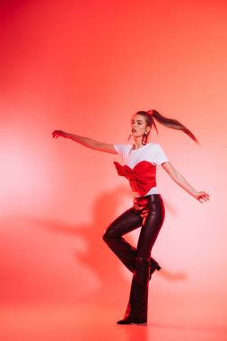 toned picture of beautiful young woman in stylish clothing dancing alone