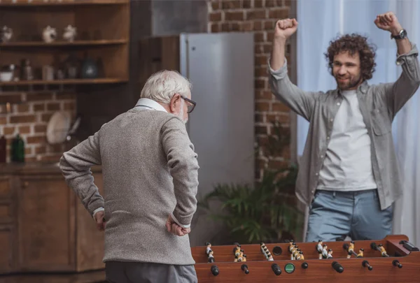 Hijo Adulto Mostrando Signo Después Ganar Padre Mayor Futbolín Casa — Foto de Stock