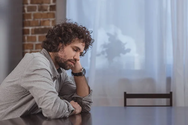 Nadenkend Knappe Man Achter Houten Tafel Thuis — Stockfoto