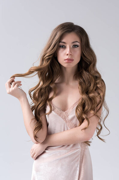 portrait of attractive girl with long curly hair, isolated on grey