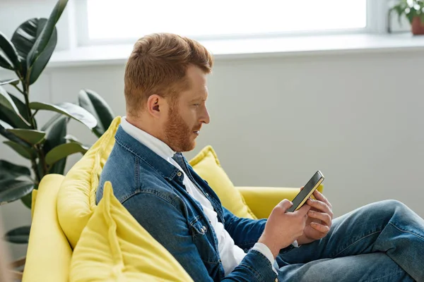 Mladý Muž Sedí Pohovce Smartphone Rukou — Stock fotografie