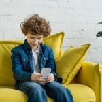 Kid looking at phone while sitting on sofa
