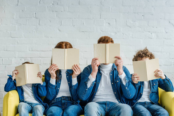 Family holding books and sitting on sofa