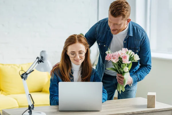 Homme Cadeau Jeune Femme Travaillant Par Ordinateur Portable Avec Bouquet — Photo