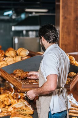 arkadan görünüşü erkek tezgâhtar süpermarkette taze ekmek düzenlenmesi