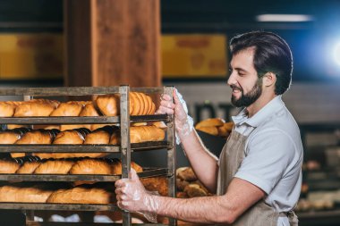 erkek tezgâhtar süpermarkette taze pasta düzenlenmesi gülümseyen