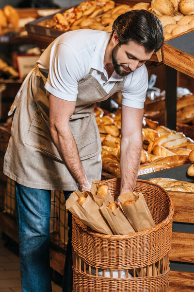 male shop assistant arranging fresh pastry in supermarket