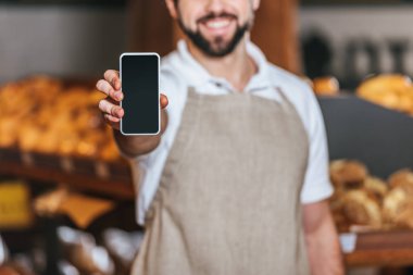 tezgâhtar gösteren smartphone süpermarkette boş ekran ile gülümseyen kısmi görünümü