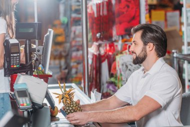 tezgâhtar süpermarkette para noktada yan görünüm