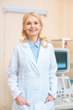happy female doctor looking at camera at ultrasound screening office clipart