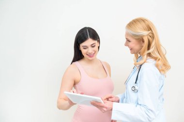 smiling obstetrician gynecologist and pregnant woman using tablet together clipart