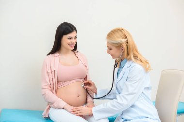 Çocuk fetus stetoskop ile hamile kadın doğum uzmanı jinekolog dinleme heartbeat