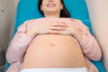 close-up shot of young pregnant woman lying on bed of maternity hospital clipart