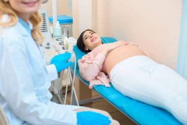 obstetrician gynecologist and pregnant woman at ultrasound scanning office clipart