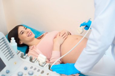 obstetrician gynecologist making ultrasound scanning for young happy pregnant woman clipart