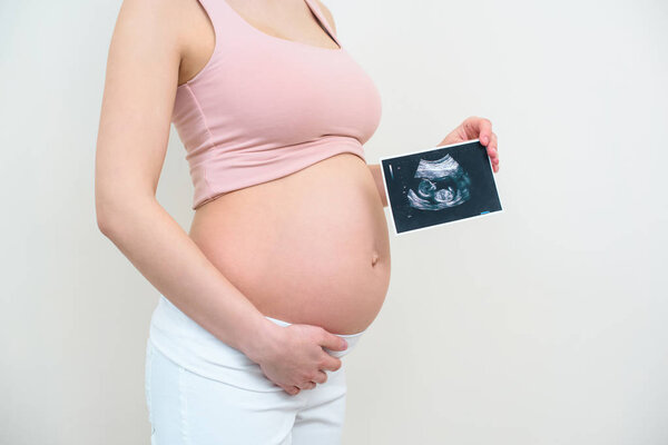 cropped shot of pregnant woman with ultrasound scan picture