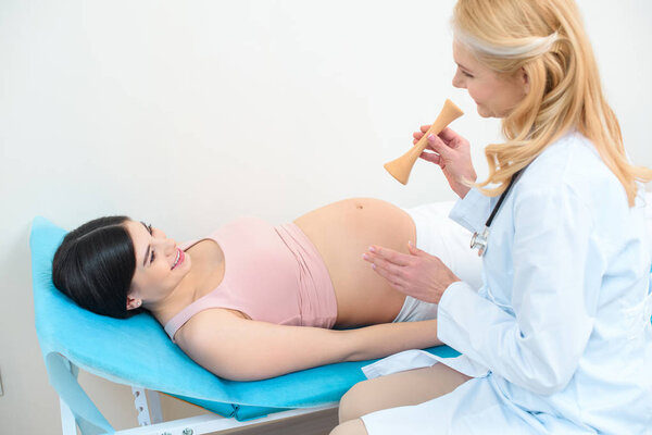 obstetrician gynecologist with traube-type stethoscope and pregnant woman