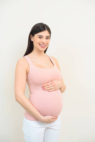 happy young pregnant woman holding her belly on white