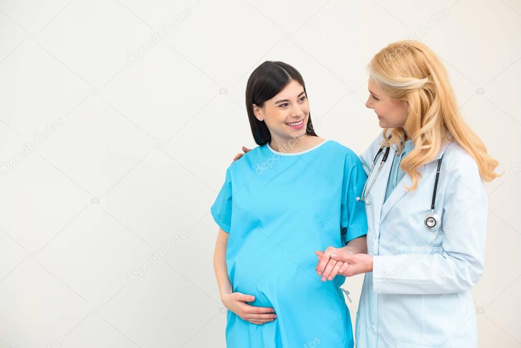 obstetrician gynecologist helping pregnant woman to walk and holding her hand