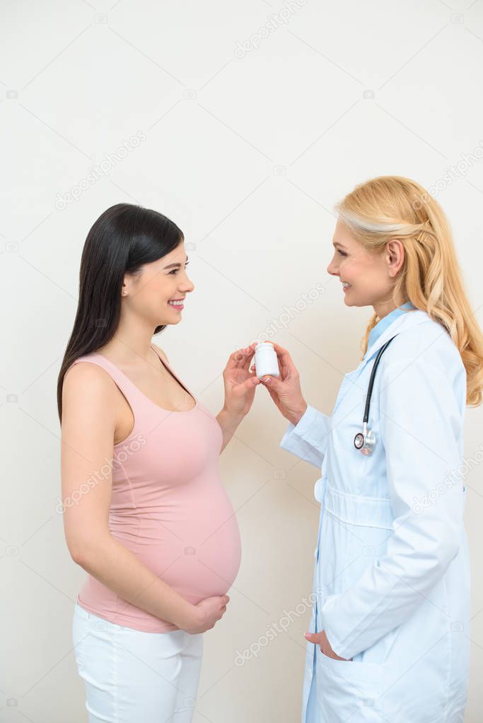 obstetrician gynecologist and pregnant woman holding jar of pills