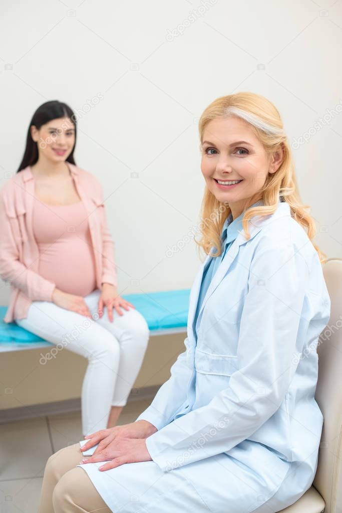 mature obstetrician gynecologist and pregnant woman at maternity hospital