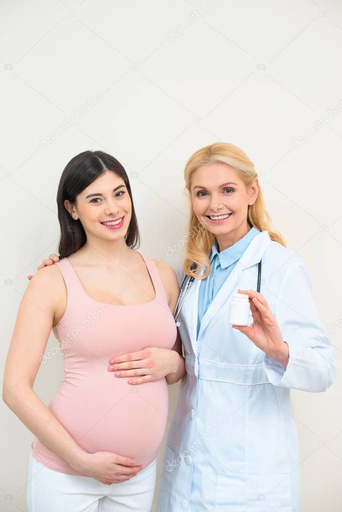 obstetrician gynecologist and pregnant woman with jar of pills looking at camera