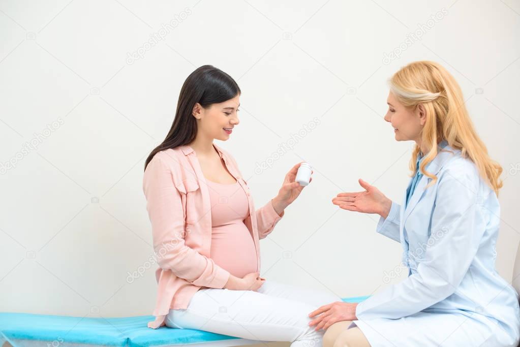 obstetrician gynecologist showing jar of pills to pregnant woman