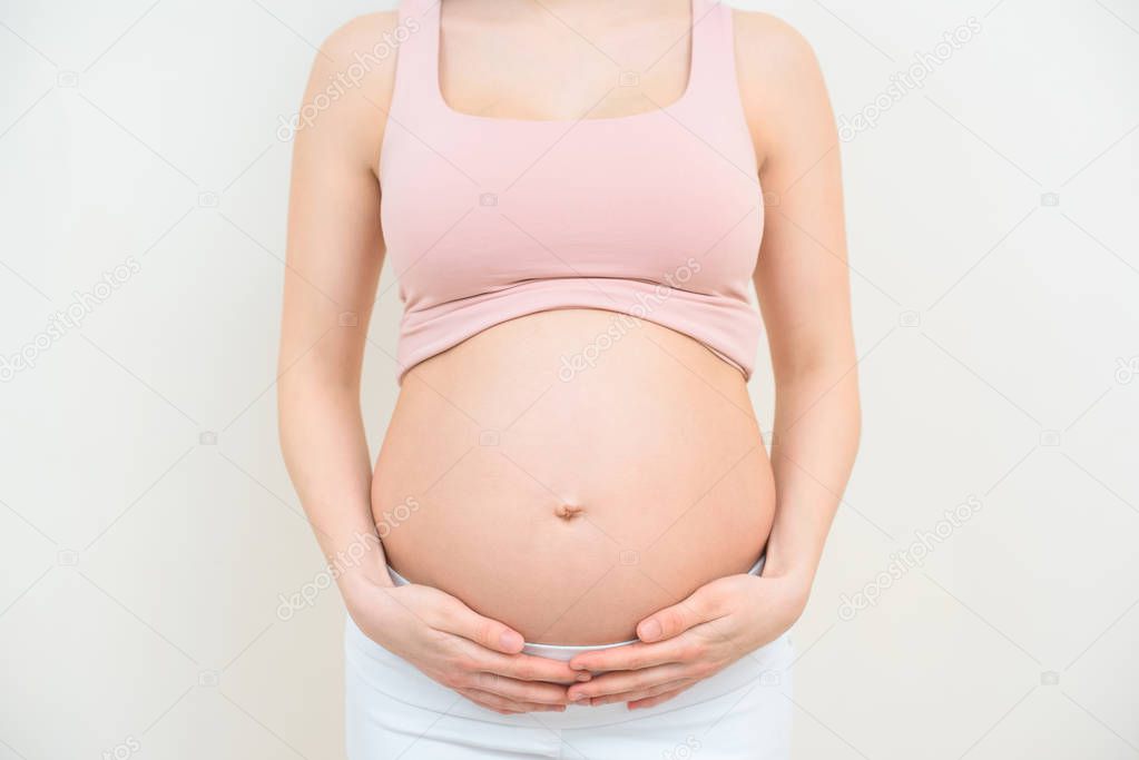 cropped shot of pregnant woman holding her belly on white