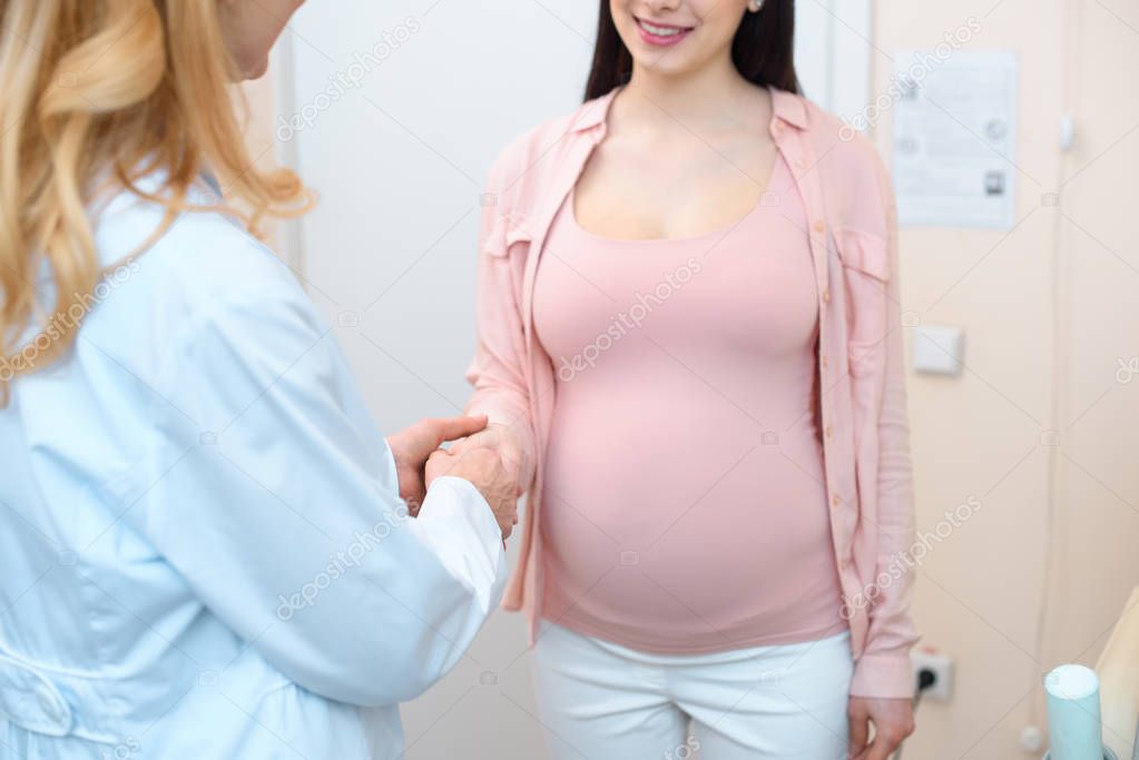 cropped shot of obstetrician gynecologist and pregnant woman shaking hands