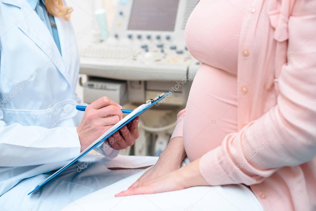 cropped shot of obstetrician gynecologist consulting pregnant woman and writing in clipboard