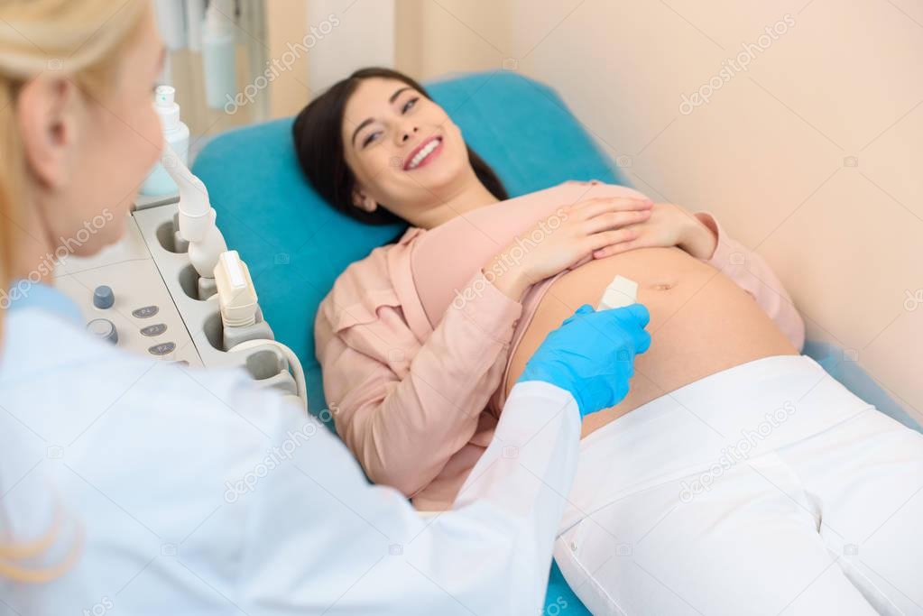 obstetrician gynecologist making ultrasound examination for young pregnant woman