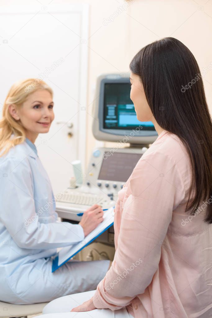obstetrician gynecologist consulting pregnant woman at ultrasound scanning office