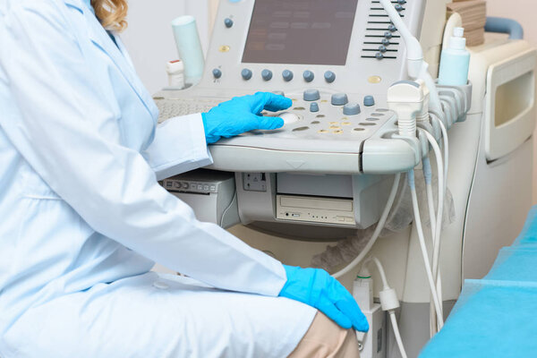 обрезанный снимок акушера-гинеколога, работающего с ультразвуковым сканером
