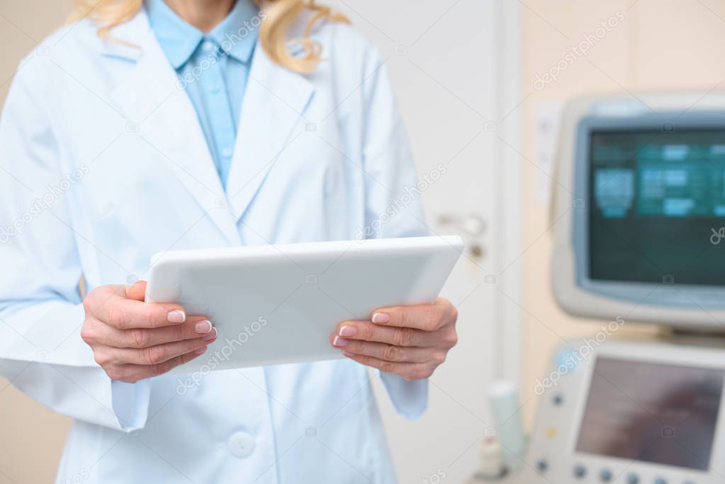 obstetrician gynecologist using tablet with ultrasonic scanner on background