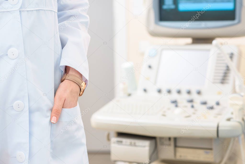 cropped shot of obstetrician gynecologist in coat with ultrasonic scanner on background