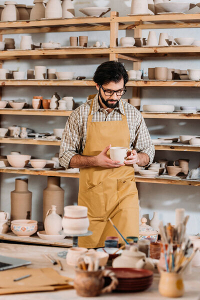 male potter with ceramic dishware in workshop