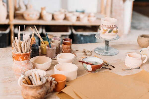 ceramics and paints on wooden table in pottery workshop