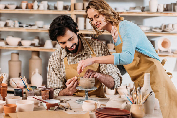 couple of potters making ceramic dishware together in workshop