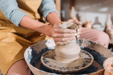 cropped view of female potter making ceramic pot on pottery wheel   clipart