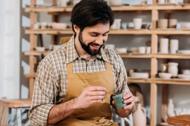 erkek çömlekçi atölyesinde holding boya ve fırça gülümseyen
