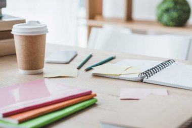 close up of educational copybooks and disposable cup of coffee on table  clipart