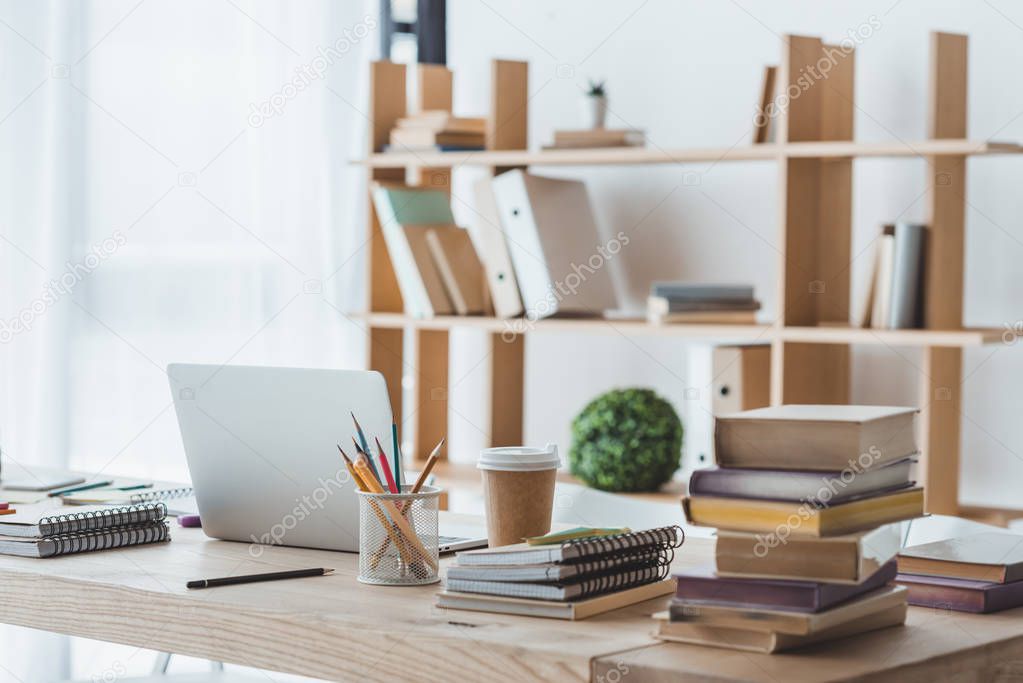 Laptop and educational books on table in light interior