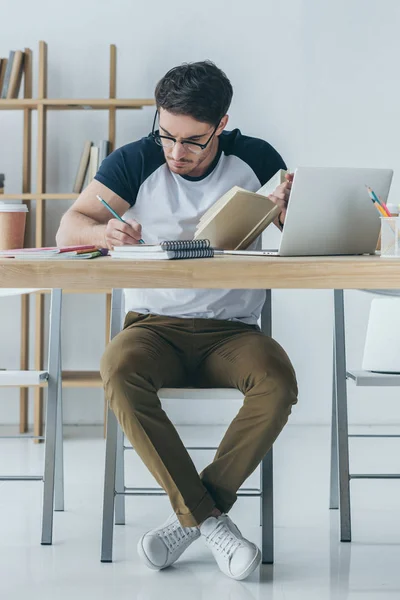 Guapo Estudiante Masculino Gafas Estudiando Con Libro Portátil — Foto de Stock