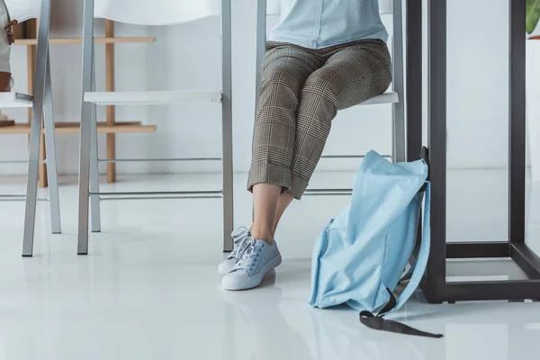 Visão Seção Baixa Menina Sentada Mesa Com Mochila Chão — Fotografia de Stock