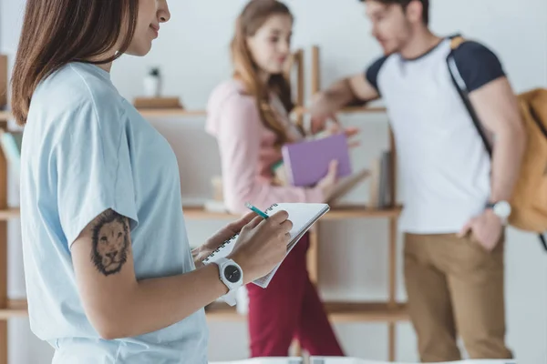 Recortado Vista Estudiante Mujer Escribiendo Copybook Mientras Que Sus Amigos — Foto de Stock