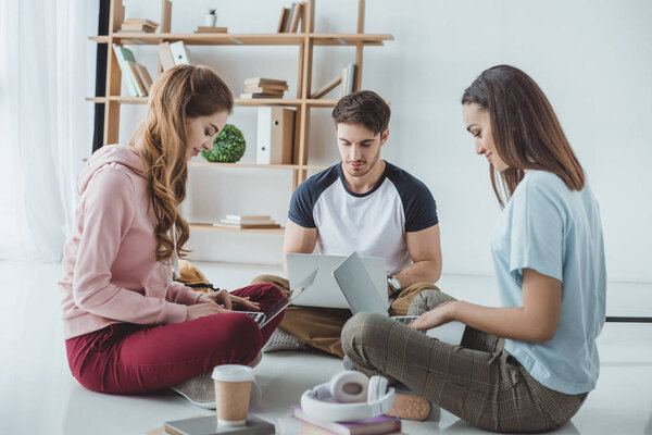 multicultural students studying with laptops, books and coffee on floor 