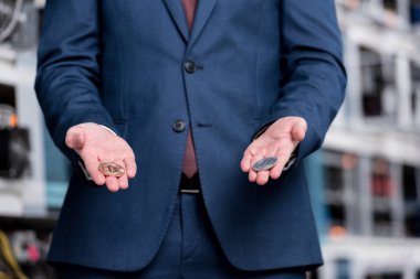 cropped shot of businessman holding bitcoins at cryptocurrency mining farm clipart