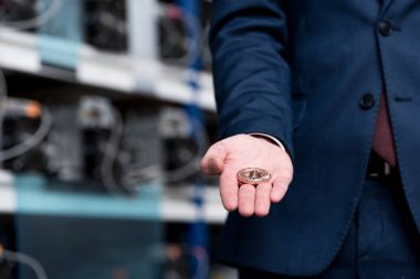 cropped shot of businessman holding bitcoin at cryptocurrency mining farm clipart